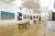 A large gallery space with wooden flooring and white walls and pop art on the walls.