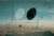 Painting by John Tunnard of imaginary abstract objects - one white and one black oval suspended in a framework and devised to exist in a 3-D space with a brown landscape beneath it and a blue background.