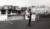 Black and white photograph depicting a couple enjoying ice cream next to a kiosk