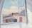 Painting by Ivon Hitchens in pale tones showing a view from a window of a blue skywith white fluffy clouds over rooftops and distant countryside