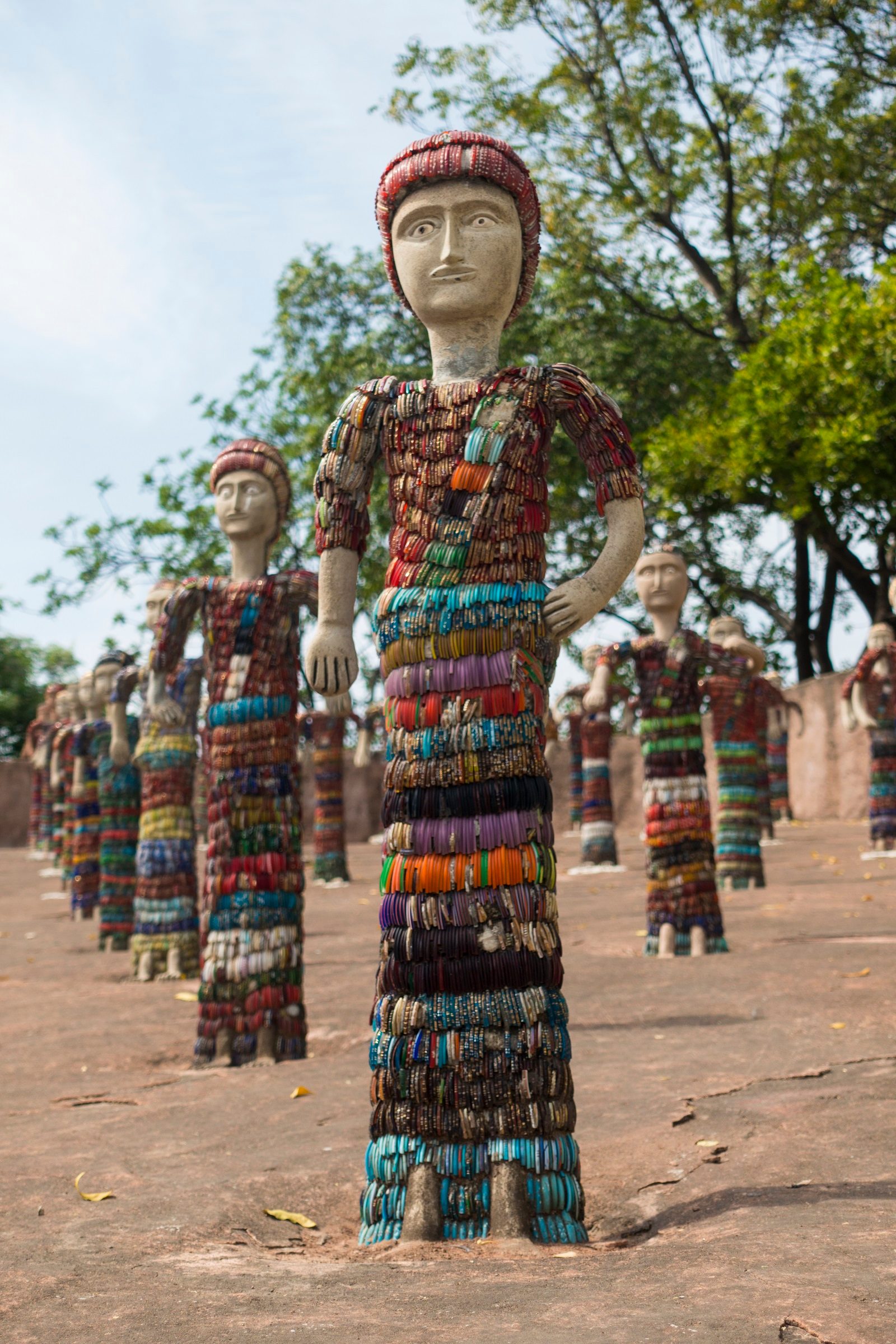 Row of brightly decorated sculptures of people made from discarded pottery fragments