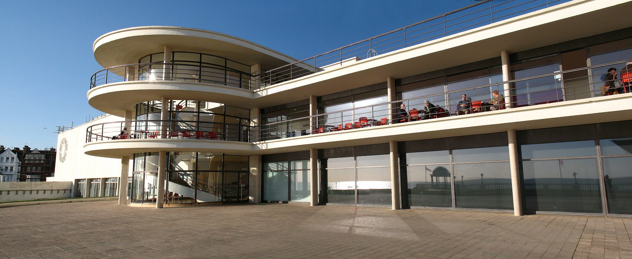 Photograph of the exterior of a building with a long colonnade and curved section jutting out beyond