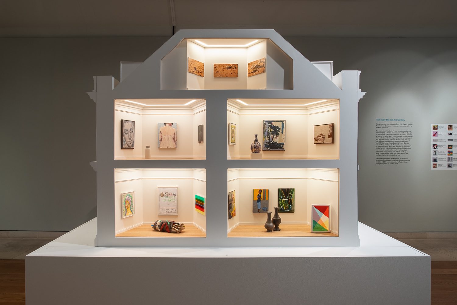 A large dollhouse sized art gallery, designed to imitate the exterior of an 18th century townhouse. The front shows a cross section of fiverooms (one in the attic, two on the first floor, and two on the ground floor), each filled with works of modern art.