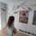 Photograph of a young girl with long dark hair looking at an artwork on a white wall