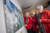Photograph of four people standing looking at an artwork on a white wall