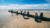 Photograph of a sandy beach with two people taking photos