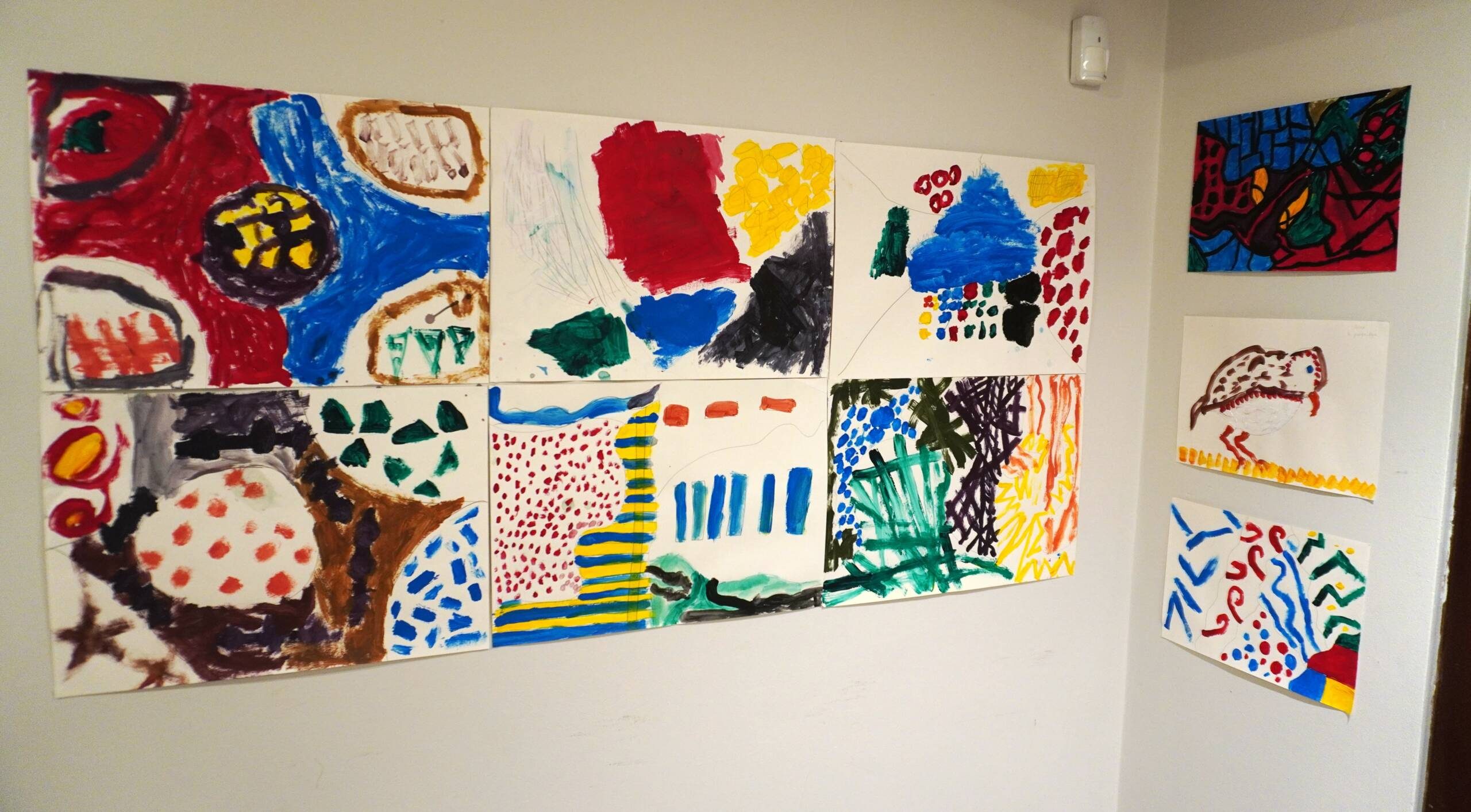 Photograph of artworks in many different colours and shapes on a white wall