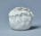 Photograph of a ceramic pot with spiral patterns and a filled edge, all in white