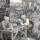 Detail from Canvassing for Votes two men sit at a table counting coins, behind in the distance them a scrum forms outside a pub.