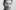 Photograph in greyscale of man with grandad collar striped shirt from chest up. He has short dark hair and stubble.
